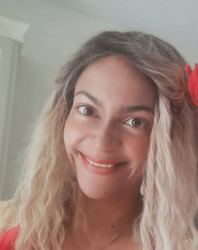 Femme Souriante aux Cheveux Blonds et Fleur Rouge Femme souriante aux cheveux blonds ondulés avec une fleur rouge.